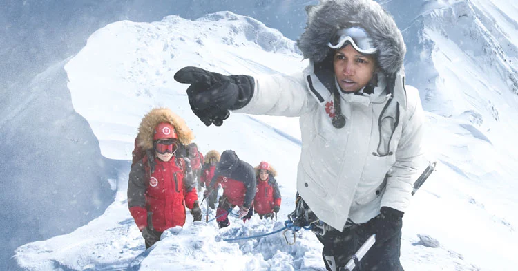 A guide leads a group of climbers, pointing toward the summit on Everest.