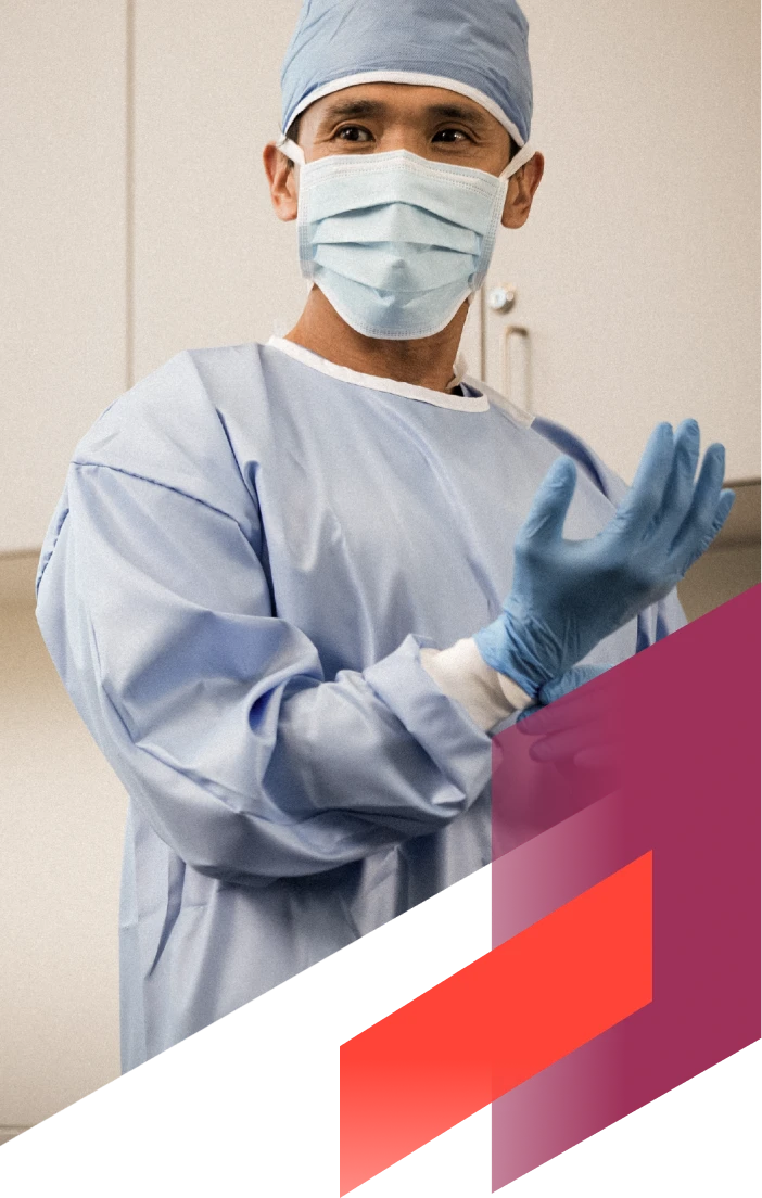 A locums surgeon in mask, scrubs, and gloves preps for work.